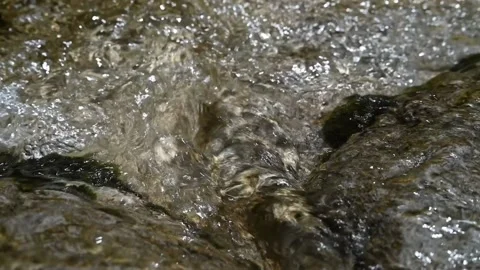 Sunlight effects on water flowing over rocks (slow motion) Video stock 212749633