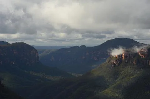 Sunlight falling on sandstone cliffs overlooking a valley filled with forest. Stock Photos