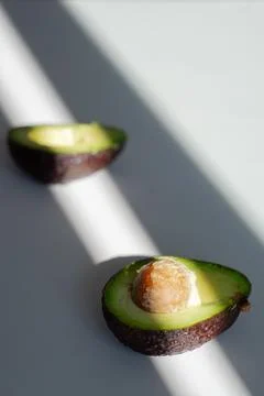 Sunlight falls on the avocado lying on the table Stock Photos