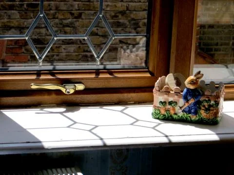 Sunlight falls on the window sill through a delicately glazed window, a ceram Stock Photos