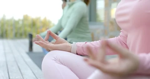 Sunlight filtering on deck guiding female friends sitting, holding gyan mudra Stock Footage 340881428