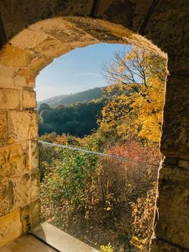 Sunlight filtering through arched opening in historic stone wall highlights Stock Photos