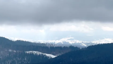 Sunlight filtering through clouds over snowy mountain range Stock Footage 312807803