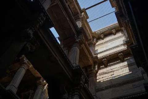Sunlight filtering through a protective metal ceiling grate onto the carved s Фото
