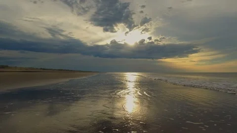 Sunlight filters through clouds over a calm ocean at sunset, creating a bea.. Stock Footage 308421014