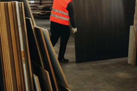 As the sunlight filters into the warehouse, a diligent worker in a bright saf Stock Photos