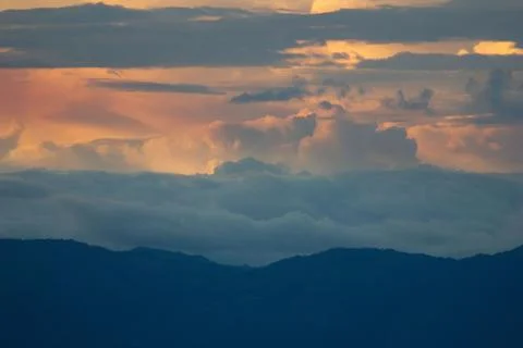 Sunlight getting through the clouds and mountains at sunset Stock Photos