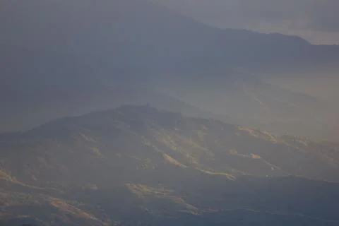 Sunlight getting through the clouds and mountains at sunset Stock Photos