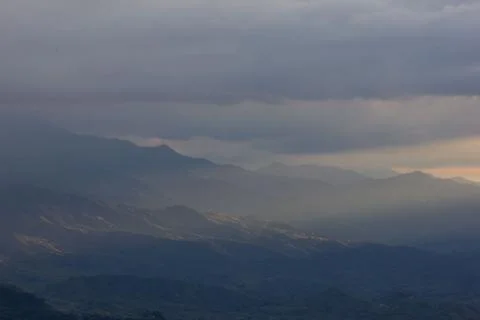 Sunlight getting through the clouds and mountains at sunset Stockfoto's