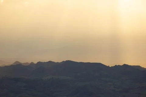 Sunlight getting through the clouds and mountains at sunset Stock Photos