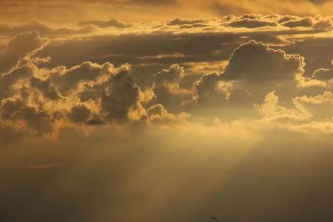 Sunlight getting through the clouds and mountains at sunset Stock Photos