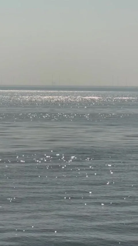 Sunlight glinting on the surface of the ocean with a hazy horizon in the Vídeos de archivo 334084445
