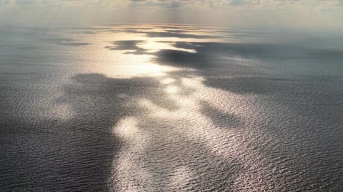 Sunlight glints across calm ocean waters from above Stock Footage 337986270