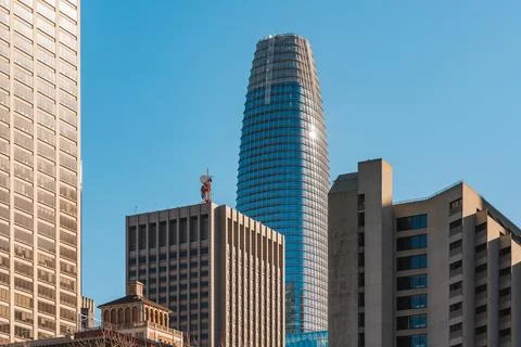 Sunlight glints off a modern cylindrical skyscraper amidst traditional buil.. Stock Photos