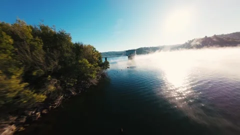 Sunlight glints on river as mist drifts at Castelo de Bode Stock Footage 342272278