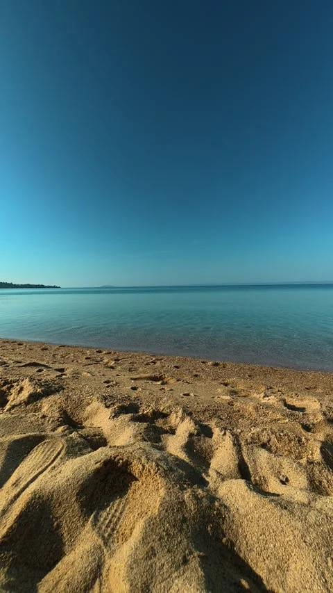 Sunlight glints softly over the shoreline. Nikiti, Greece. Vertical Vídeos de archivo 338357529