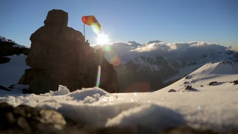 Sunlight glistens off snow  in front of a wind sock and snowy mountain range Stock Footage 90878937