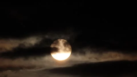 Sunlight glowing behind dark moving clouds during a dramatic sunrise or sunset Stock Footage 342326479
