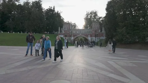 Sunlight Glows Behind the Figured Bridge as Visitors Cross the Plaza Stock Footage 340355918