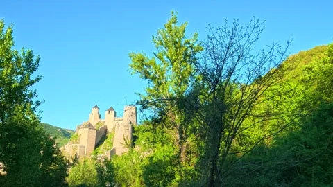 Sunlight glows on mossy hillside and castle walls. Balkan, Eastern Europe, POV Stock Footage 333348026