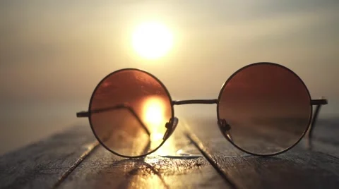 Sunlight Goes Throw the Round Glasses Lying on the Wooden Table. Slow Motion Stockbeeldmateriaal 67120648