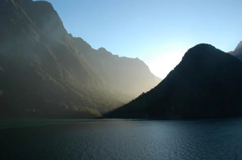 Sunlight haze falling between mountains by a lake. Stock Photos