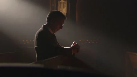 Sunlight on head and shoulders of praying man alone in church pew Stock Footage 59547894