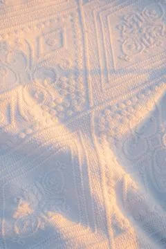 Sunlight highlights patterns on  white textile during early morning hours . S Stock Photos