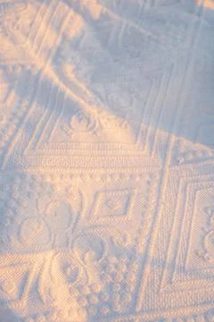Sunlight highlights patterns on  white textile during early morning hours . S Stock Photos