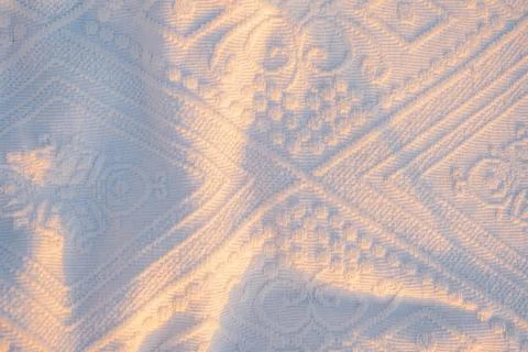 Sunlight highlights patterns on  white textile during early morning hours . S Stock Photos
