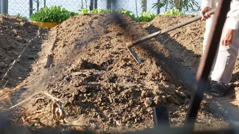 Sunlight hits a field of brown soil while a person works through rows with a Stock Footage 312214143