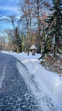 Sunlight hitting a snowy stone path winding through a quiet winter park wit.. Stock Photos