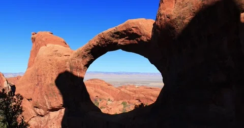Sunlight illuminates the classic shape of Landscape Arch in a bright blue sky Stock Footage 333991147