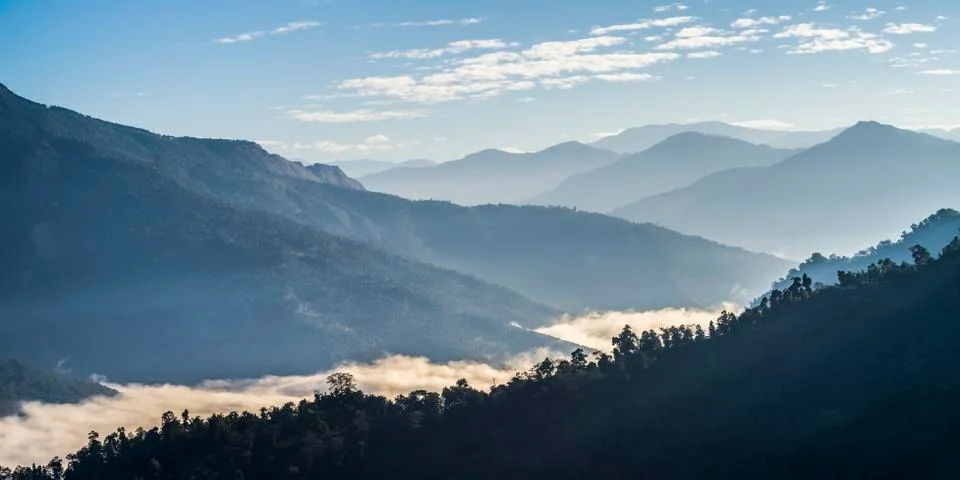 Sunlight illuminates the clouds lying low in the valley in the Himalayas Stock Photos