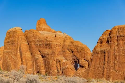 Sunlight illuminates dramatic red rock formations against blue sky Foto stock