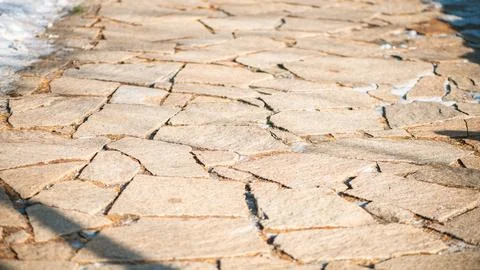 Sunlight illuminates an irregular stone paving, creating a rustic and textu.. Stock Photos