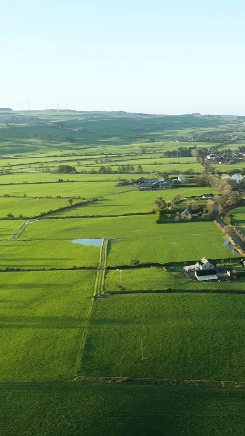 Sunlight illuminates a patchwork of green fields, farms, and trees. 스톡 동영상 315341344