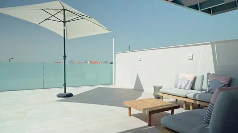Sunlight illuminates a pristine white terrace, complete with a parasol Stock Footage 320893253