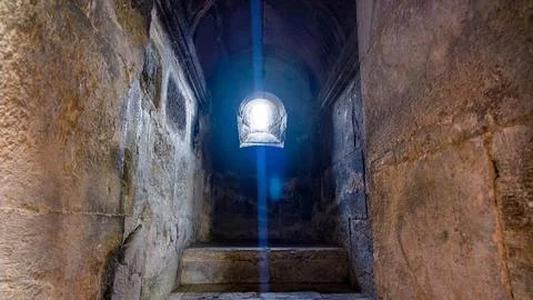 Sunlight illuminates stone steps in ancient underground passage Stock Photos