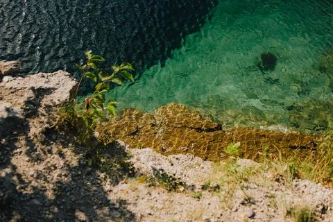 Sunlight illuminating bottom of pristine body of water near rocky shore Stock Photos