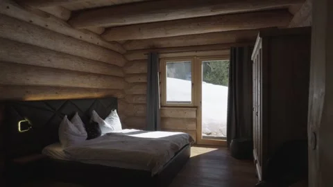 Sunlight illuminating a comfortable bed in a rustic wooden cabin bedroom with 스톡 동영상 335198872