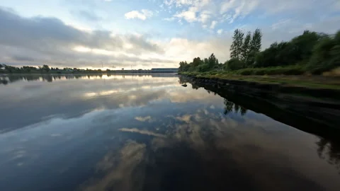 Sunlight illuminating mirror like lake surface, reflecting cloudy sky along Video stock 306398863