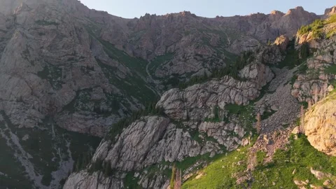 Sunlight illuminating rocky mountain range with lush green valley Video stock 312447209