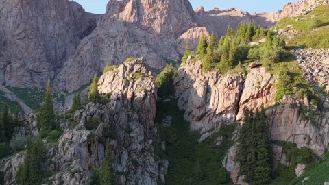 Sunlight illuminating rugged mountain peaks and lush green slopes Stock Footage 312447435