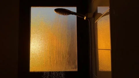 Sunlight illuminating shower with water falling against frosted glass window Stock Footage 295205650