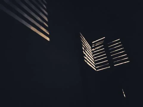 Sunlight illuminating to wall from window of closed metallic door cage in dar Stock Photos