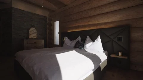 Sunlight moving across an empty bed in a rustic wooden chalet bedroom interior Stock-Footage 335756851