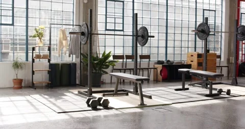 Sunlight is moving through windows casting shadows across bench, barbell and Stock Footage 337289187