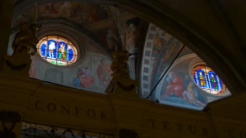 Sunlight passing through stained glass windows illuminating church frescoes 库存影片 330534395