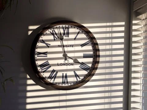 Sunlight patterns on a wall with a clock. 스톡 사진